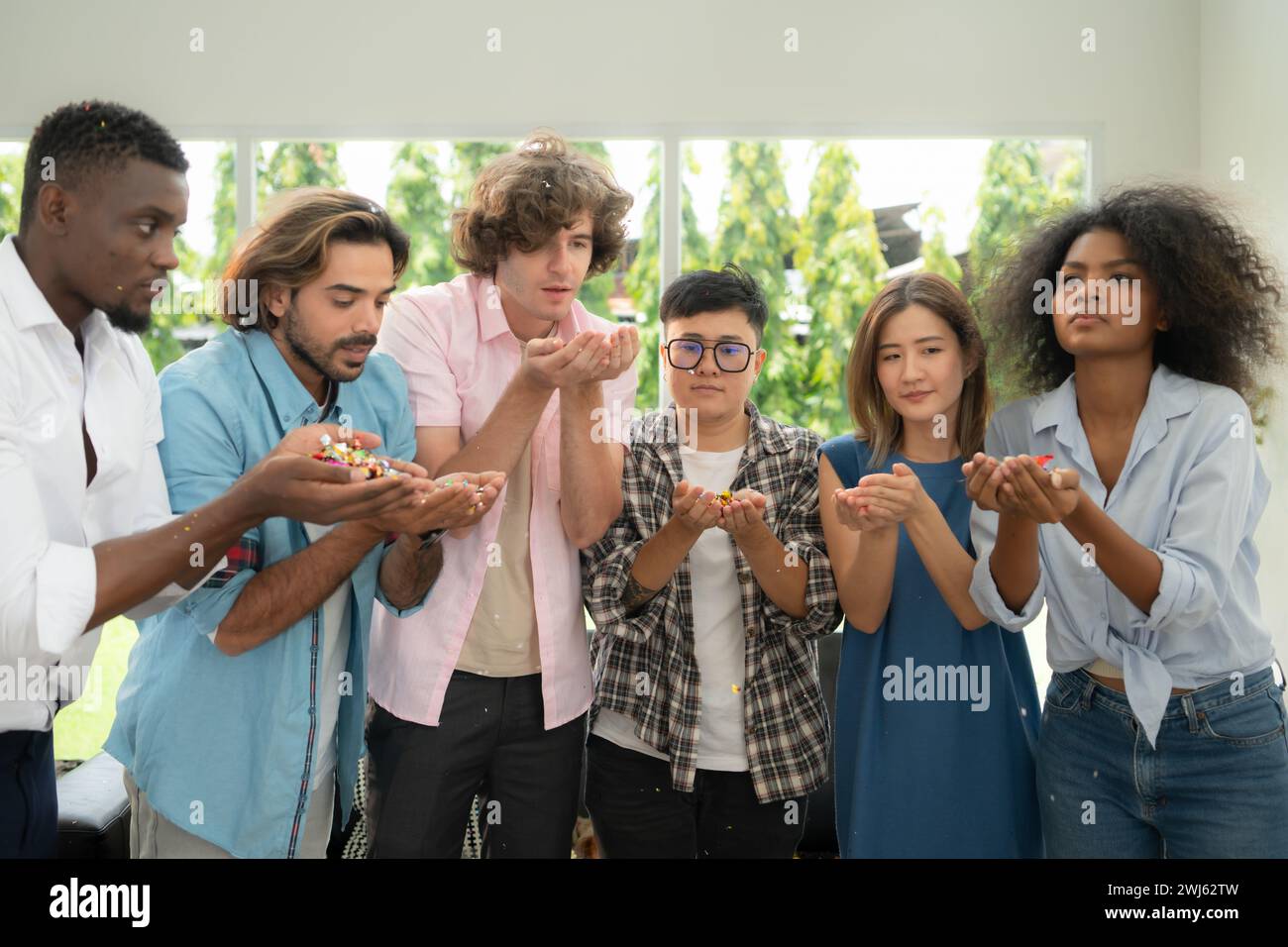 Groupe d'amis multiethniques s'amusant à la fête en jouant amusant souffler du papier coloré Banque D'Images