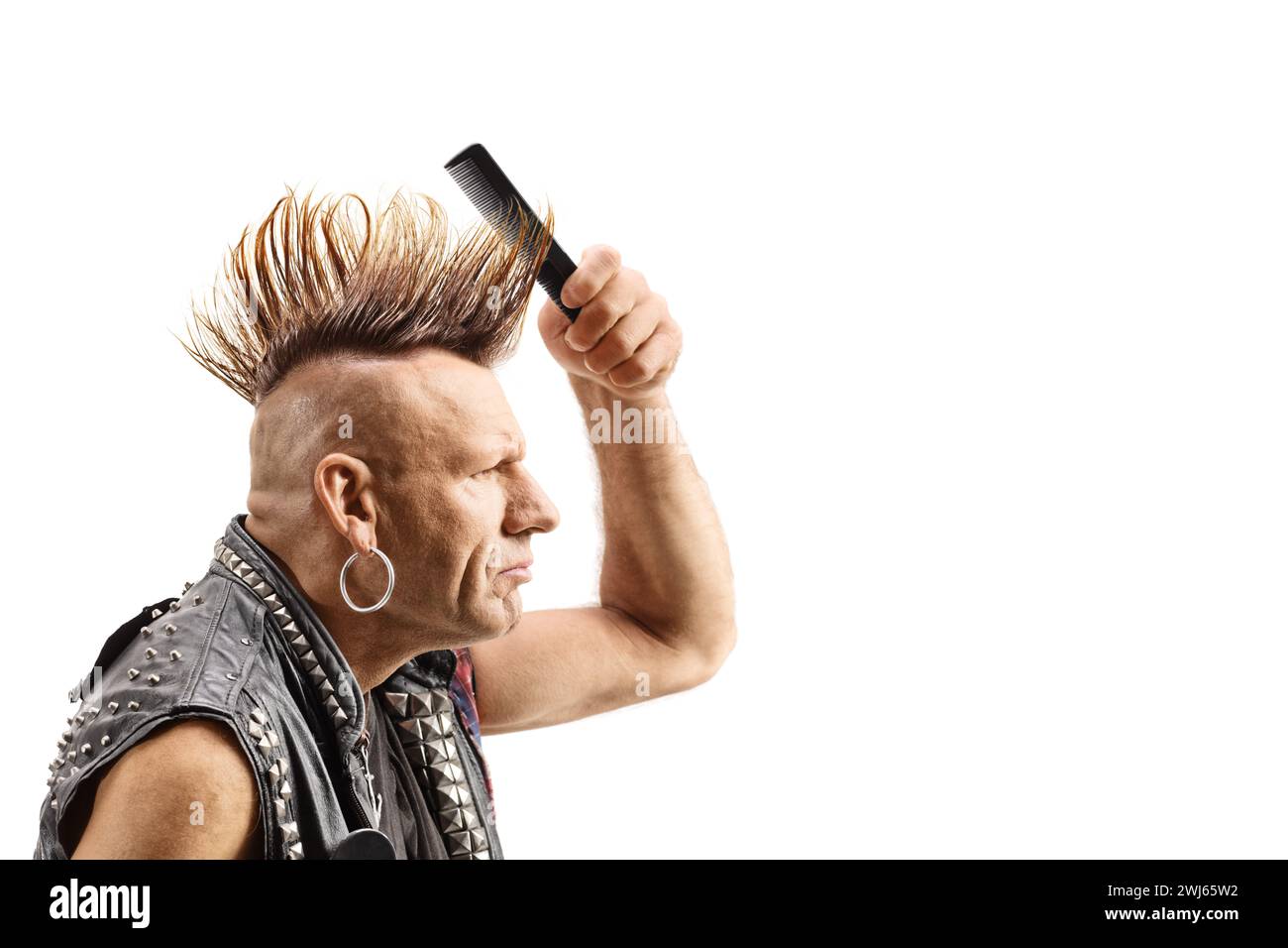 Punk fixant sa coiffure mohawk avec un peigne isolé sur fond blanc Banque D'Images