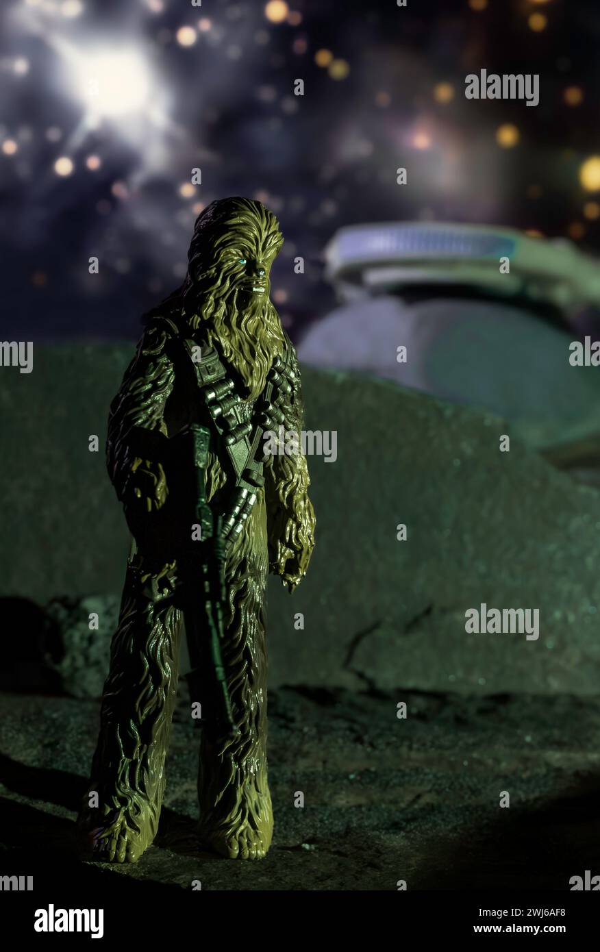 Figurine Chewbacca placée sur une planète rocheuse avec le Faucon Millenium en arrière-plan contre un ciel étoilé Banque D'Images