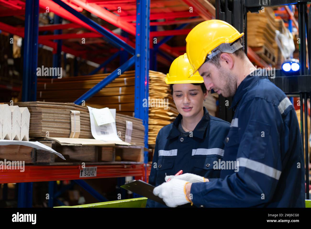 Les deux employés de l'entrepôt travaillant ensemble dans un grand entrepôt de papier utilisant une tablette Banque D'Images