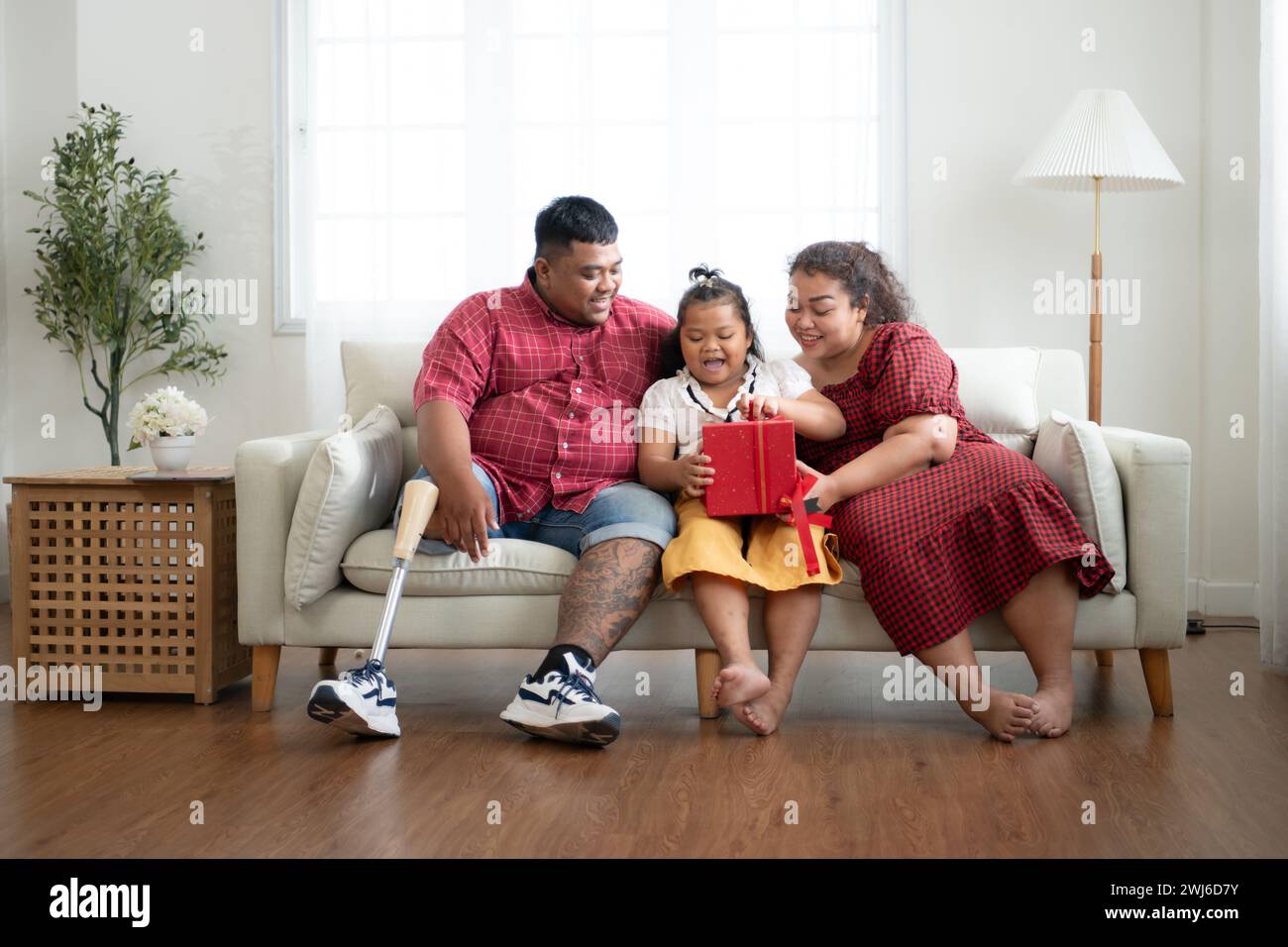 Une grande famille avec un père portant une jambe prothétique, offrir un cadeau à une fille qui réussit bien à l'école et reçoit acclai Banque D'Images