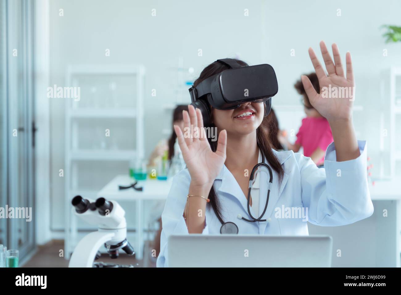 Jeune scientifique utilisant un casque de réalité virtuelle pendant que des collègues travaillent en arrière-plan au laboratoire Banque D'Images