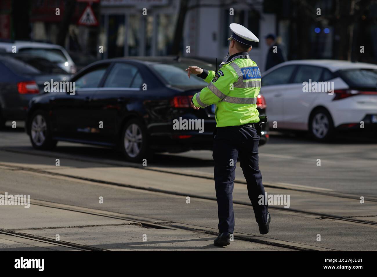 Bucarest, Roumanie - 13 février 2024 : agent de la police routière roumaine gère la circulation dans une rue animée. Banque D'Images