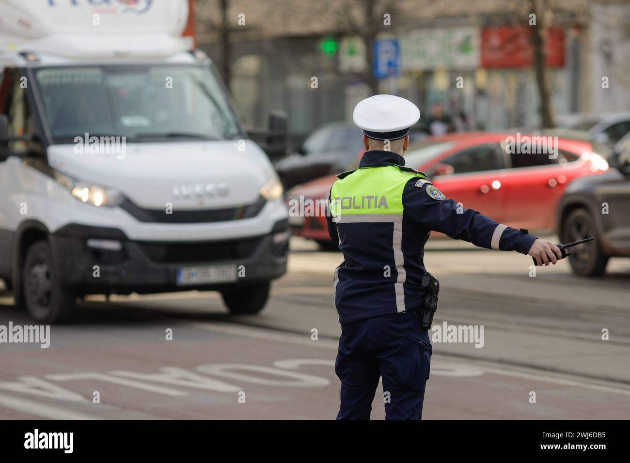 Bucarest, Roumanie - 13 février 2024 : agent de la police routière roumaine gère la circulation dans une rue animée. Banque D'Images