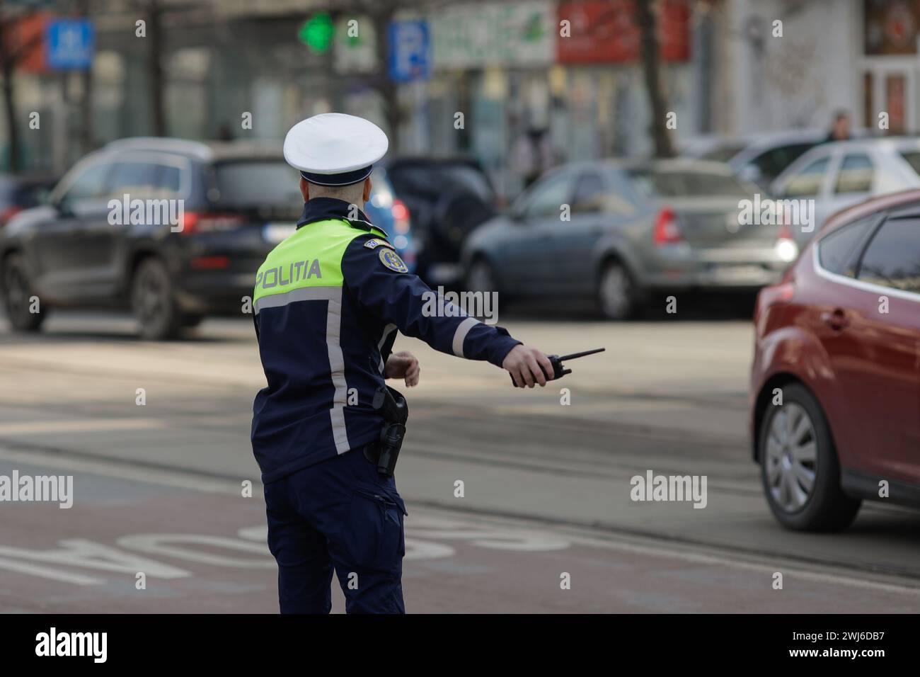 Bucarest, Roumanie - 13 février 2024 : agent de la police routière roumaine gère la circulation dans une rue animée. Banque D'Images