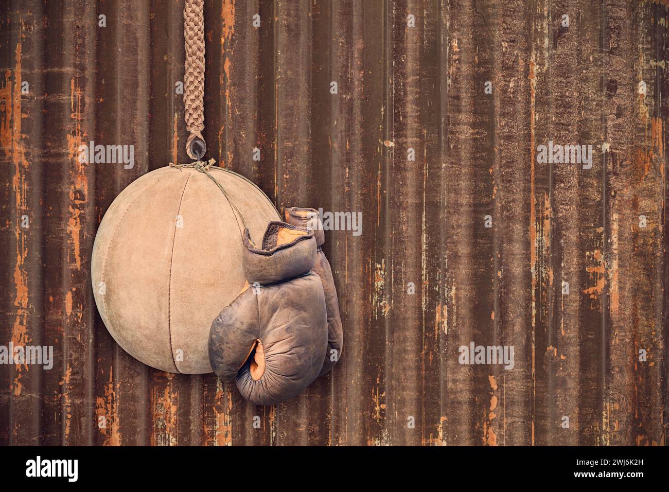 Gants de boxe en cuir vintage et ballon d'entraînement devant un mur en acier vieilli Banque D'Images