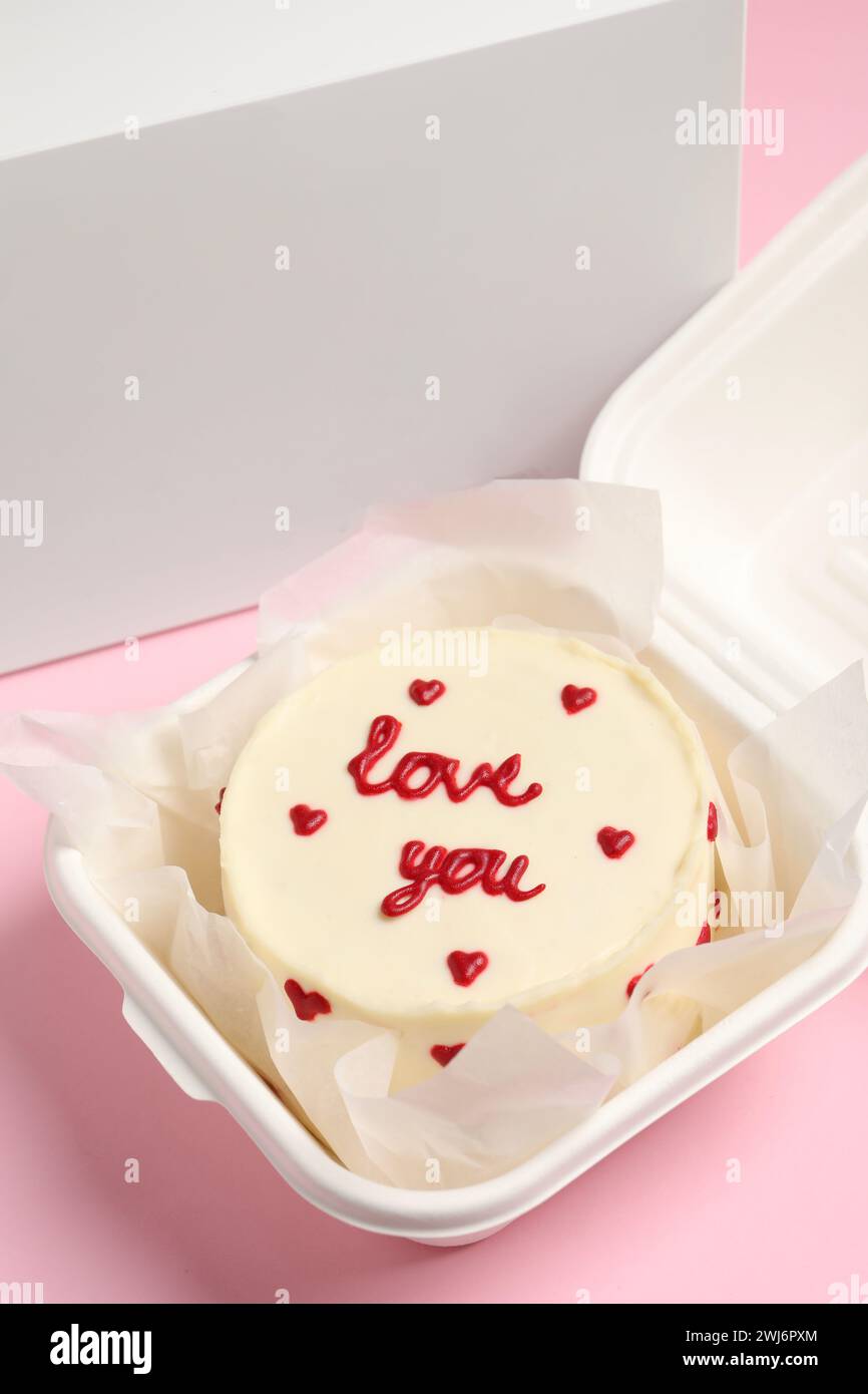 Gâteau bento savoureux avec inscription Love You dans une boîte à emporter sur une table rose Banque D'Images