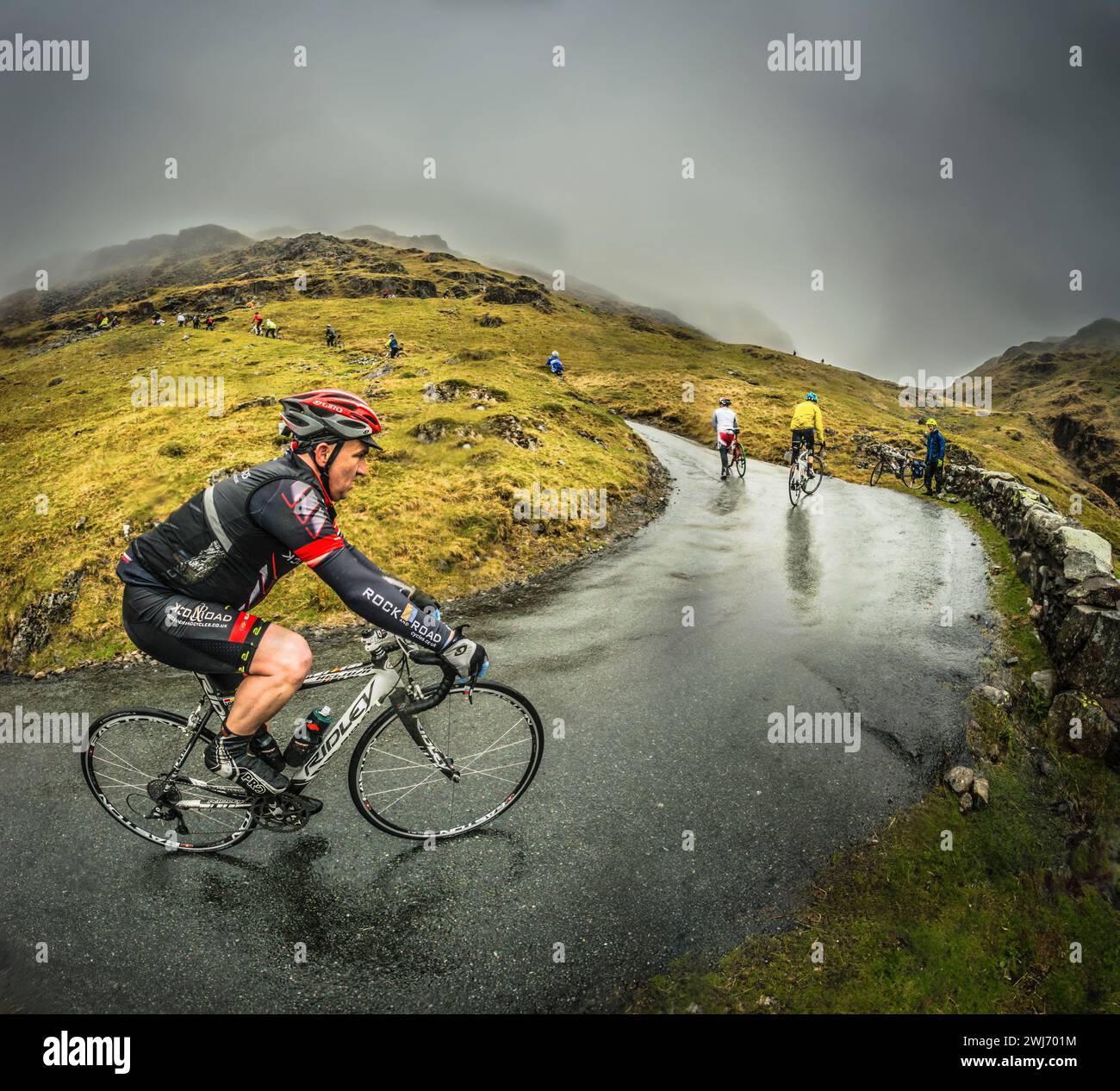 Une journée très humide dans le Lake District pour les coureurs du défi cycliste Fred Whitton 2013, vu ici sur Hardknott Pass, la route la plus escarpée d'Angleterre. Banque D'Images