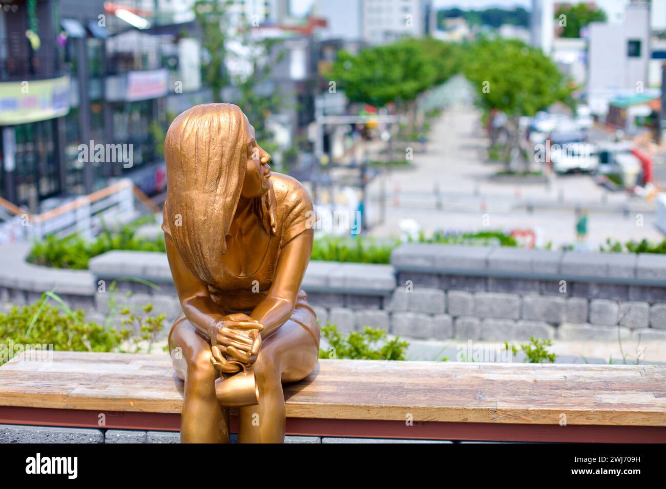 Gangneung City, Corée du Sud - 29 juillet 2019 : une statue dorée d'une jeune femme est assise sur un banc de parc surplombant Wolhwa Street dans le centre-ville de Gangneung, Banque D'Images