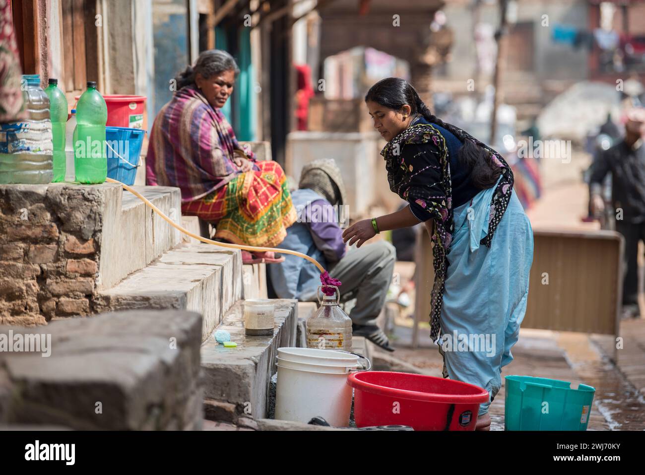 Katmandou, Népal- avril 20,2023 : les femmes lavent vêtements et vaisselle dans les rues de la place Patan Durbar. Banque D'Images Katmandou, Népal- avril 20,2023 : les femmes lavent vêtements et vaisselle dans les rues de la place Patan Durbar. Banque D'Images