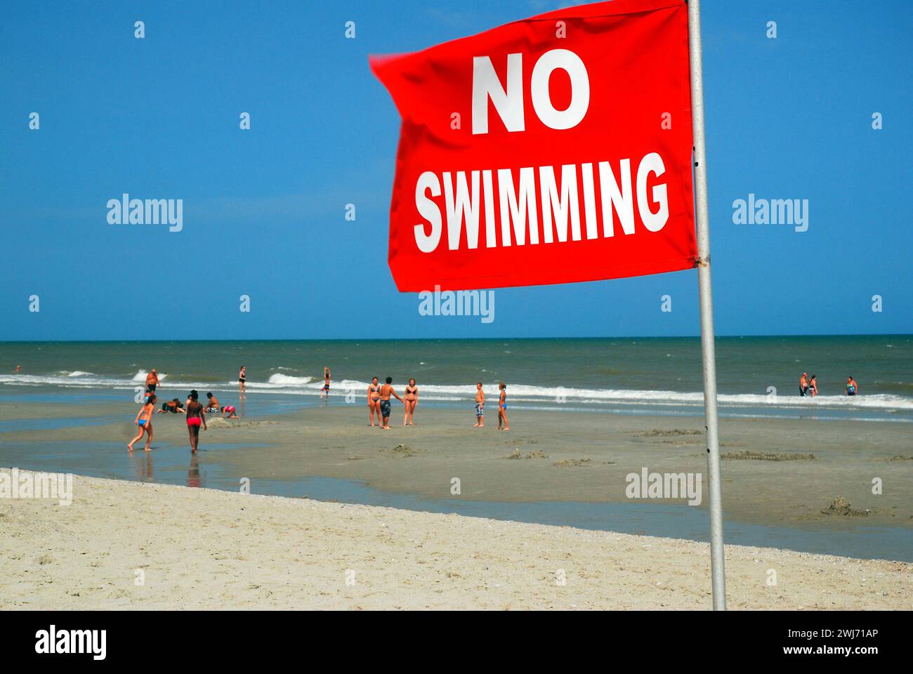 Malgré l'avertissement de sécurité No Swimming, les gens à la plage continuent à patauger dans les eaux océaniques, quels que soient les dangers Banque D'Images