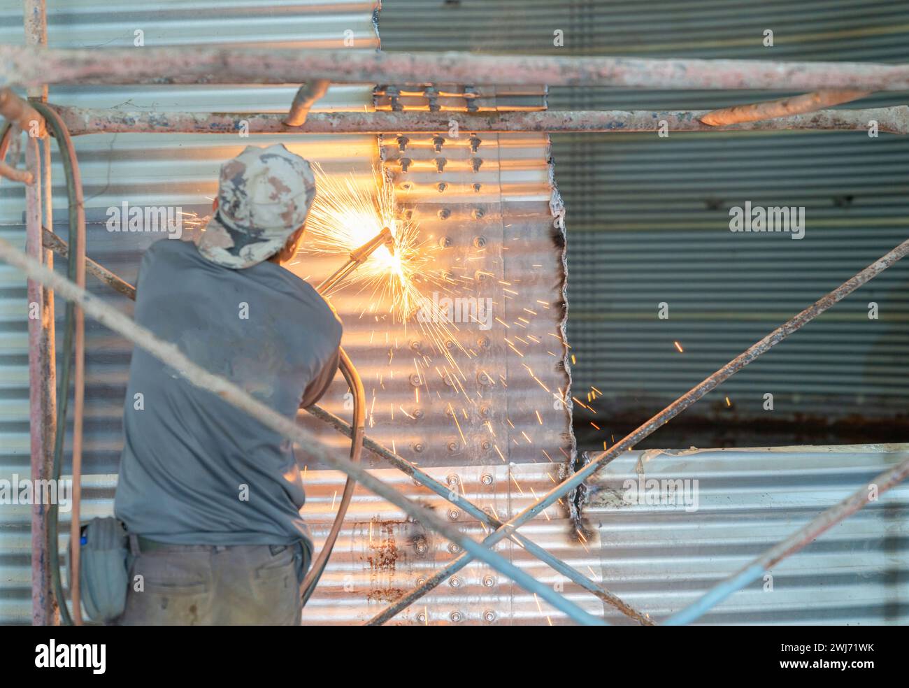 Ouvrier coupant mur métallique avec torche de coupe de métal pour enlever le réservoir d'eau. Banque D'Images