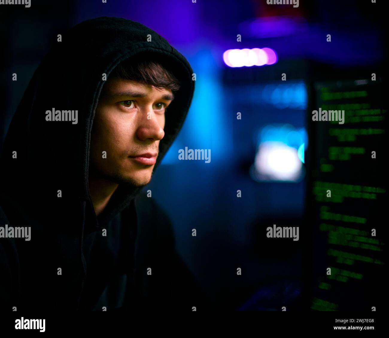 Photo d'un pirate informatique masculin assis devant des écrans violant la cybersécurité Banque D'Images