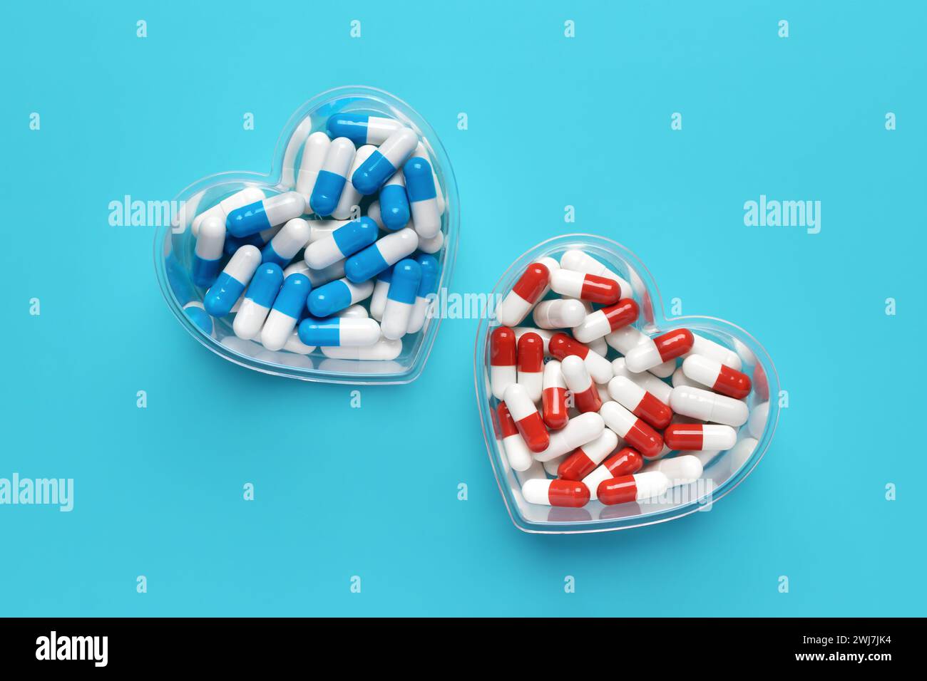 Gros plan en forme de coeur de pilules colorées sur fond bleu, capsules médicales, vue de dessus. La Saint-Valentin. Compléments alimentaires. Assortiment de produits pharmaceutiques Banque D'Images