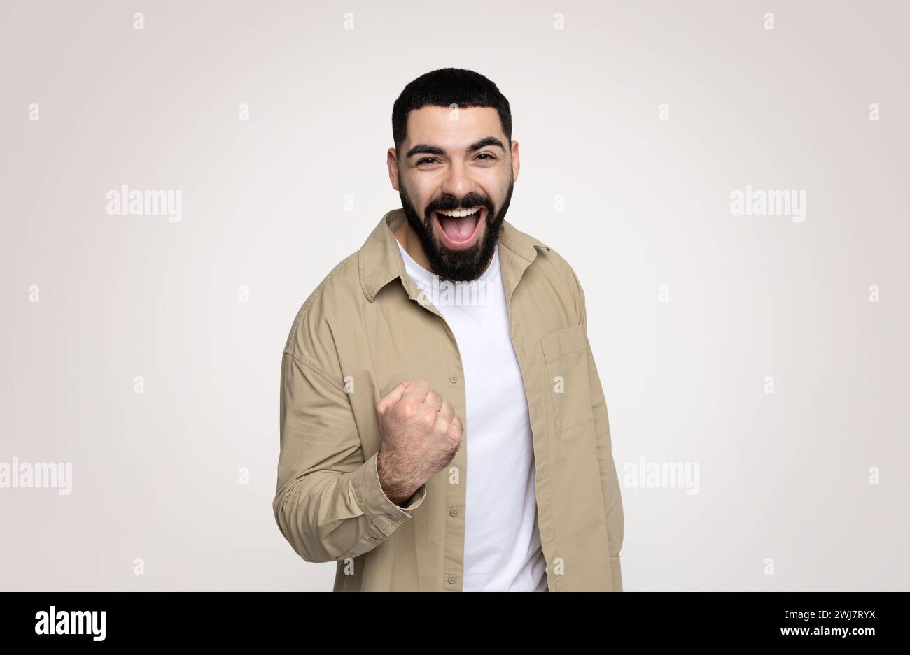 Joyeux choqué beau jeune homme latin avec la barbe dans le décontracté avec la bouche ouverte Banque D'Images