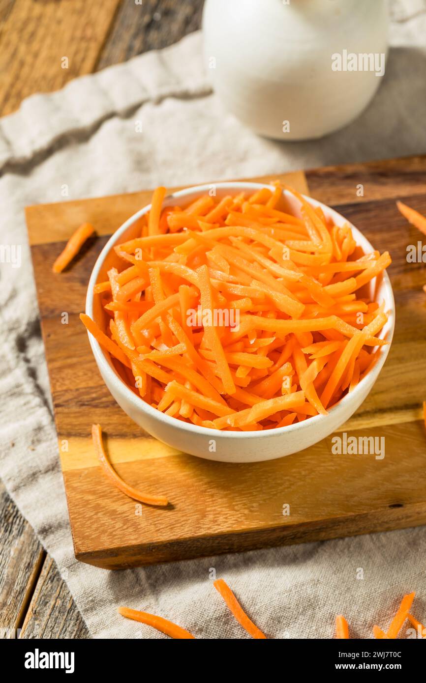 Lambeaux de carottes râpées crues biologiques dans un bol Banque D'Images