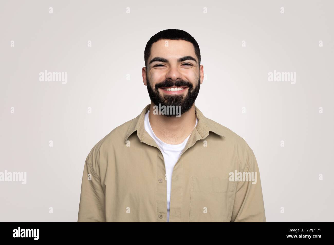 Souriant beau jeune latin gars avec une barbe dans décontracté regardant la caméra Banque D'Images