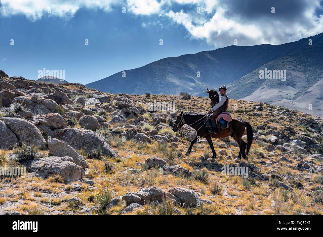 Chasseur traditionnel d'aigle kirghize dans les montagnes chassant à cheval, près de Kysyl-Suu, Kirghizistan Banque D'Images
