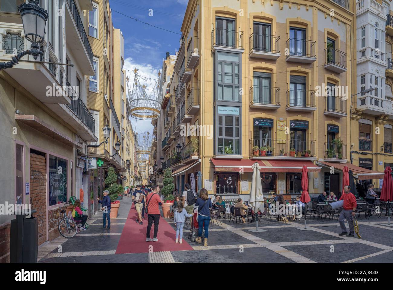 Les gens marchant sur un tapis rouge sur le sol de la rue Trapper pleine de boutiques et de décorations de Noël dans la capitale de la région de Murcie, en Espagne. Banque D'Images