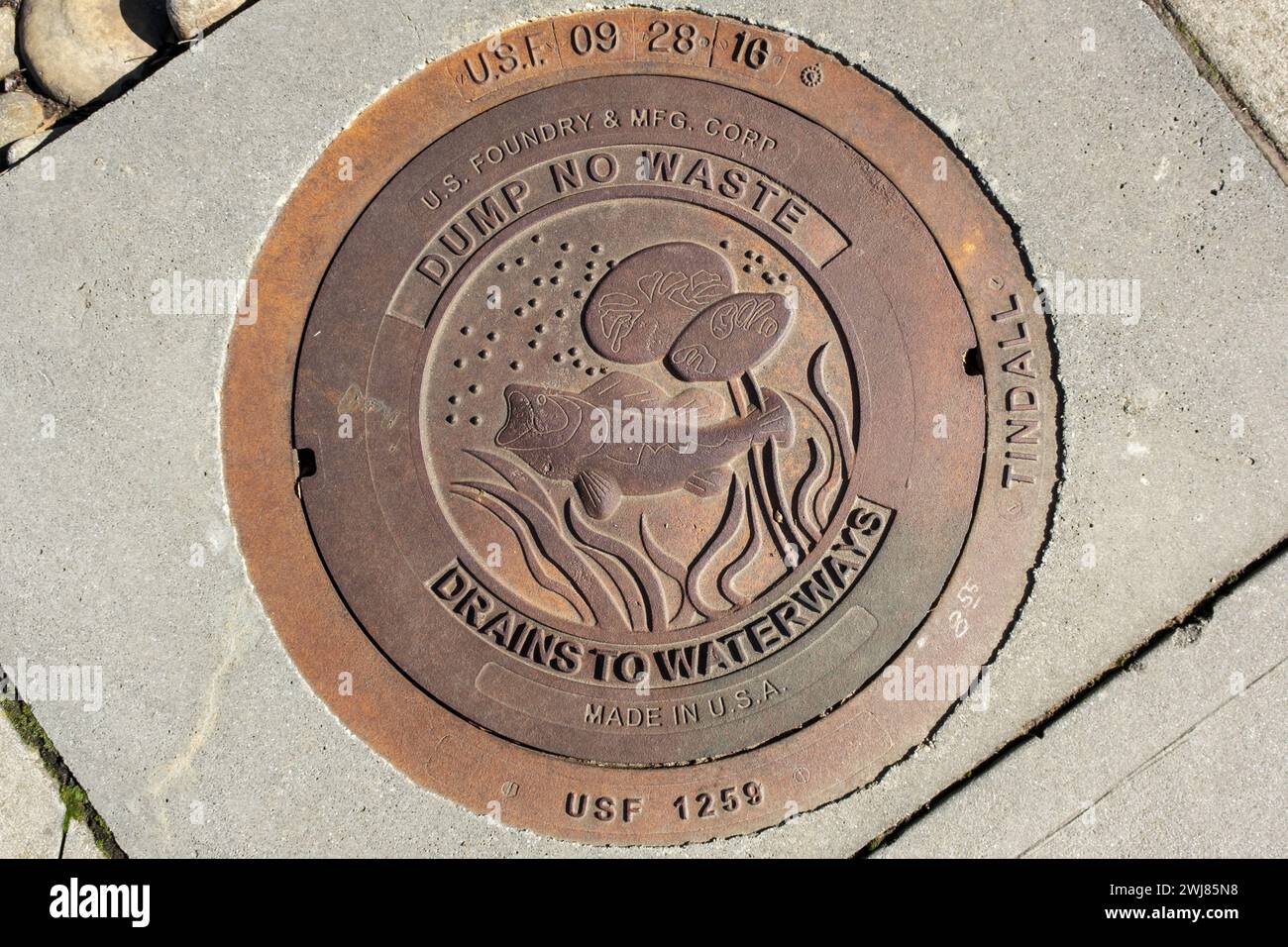 Jetez les drains sans déchets dans le couvercle de drain de trou d'homme des voies navigables sur le trottoir avec le motif poisson dessus Banque D'Images