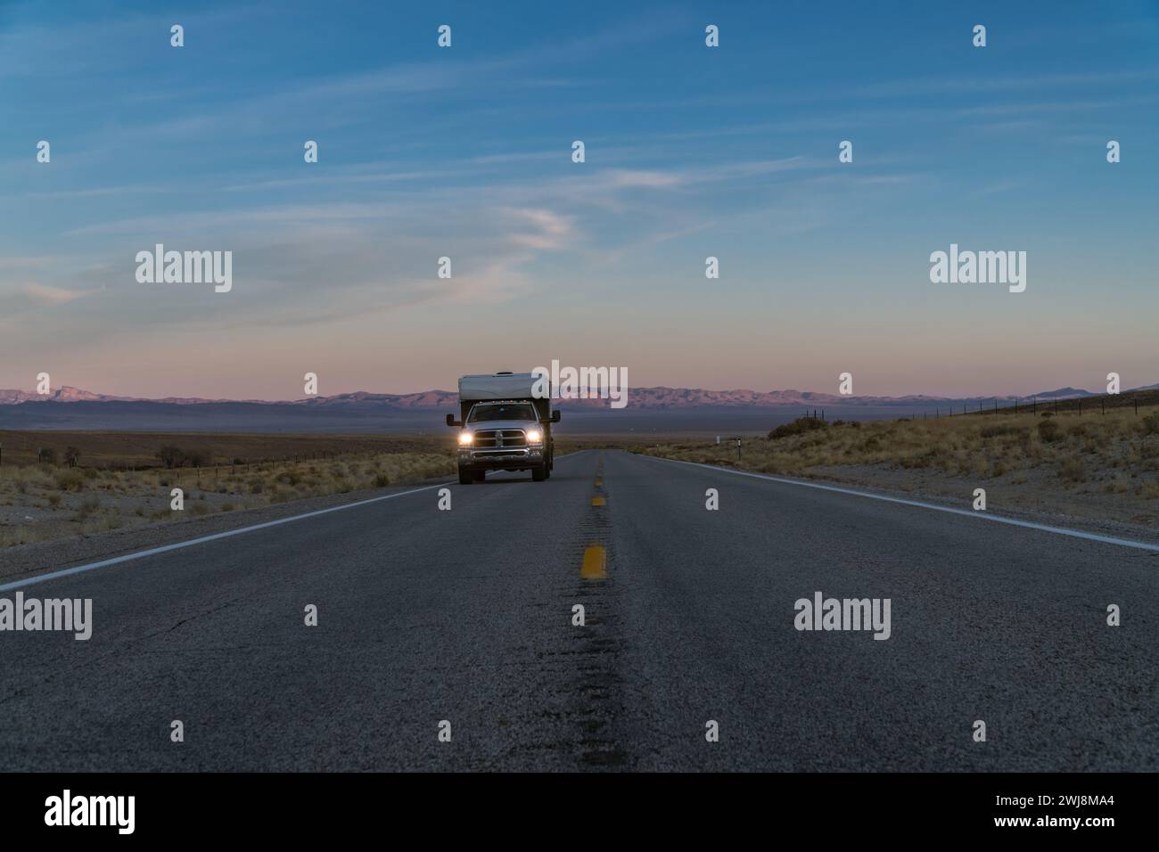 Ely, NV, US-3 novembre 2023 : camping-car camion ou camping-car de camping-car conduisant le long d'une route déserte dans le désert du Nevada au coucher du soleil. Banque D'Images