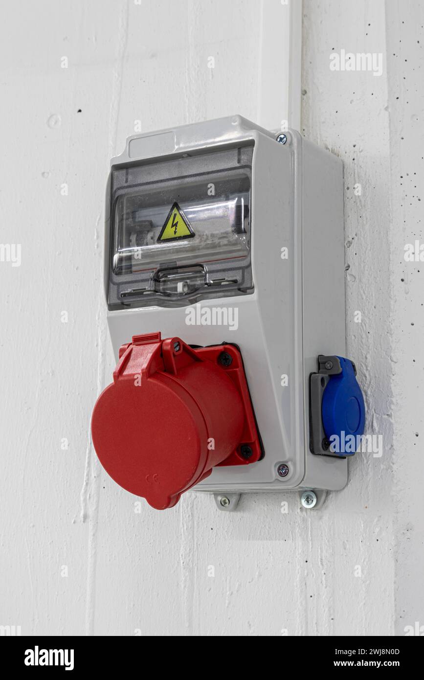 Boîtier électrique extérieur avec appareils électriques monophasés et triphasés et prises de courant. Connecteurs triphasés. Dans un hall d'usine, rouge et Banque D'Images