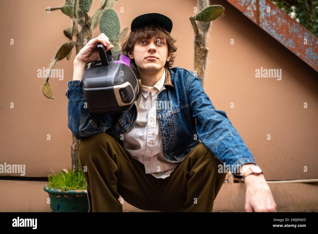 Jeune hipster masculin élégant porté dans le style rétro à l'ancienne des années 90 tenir lecteur d'enregistreur de cassette audio. Banque D'Images