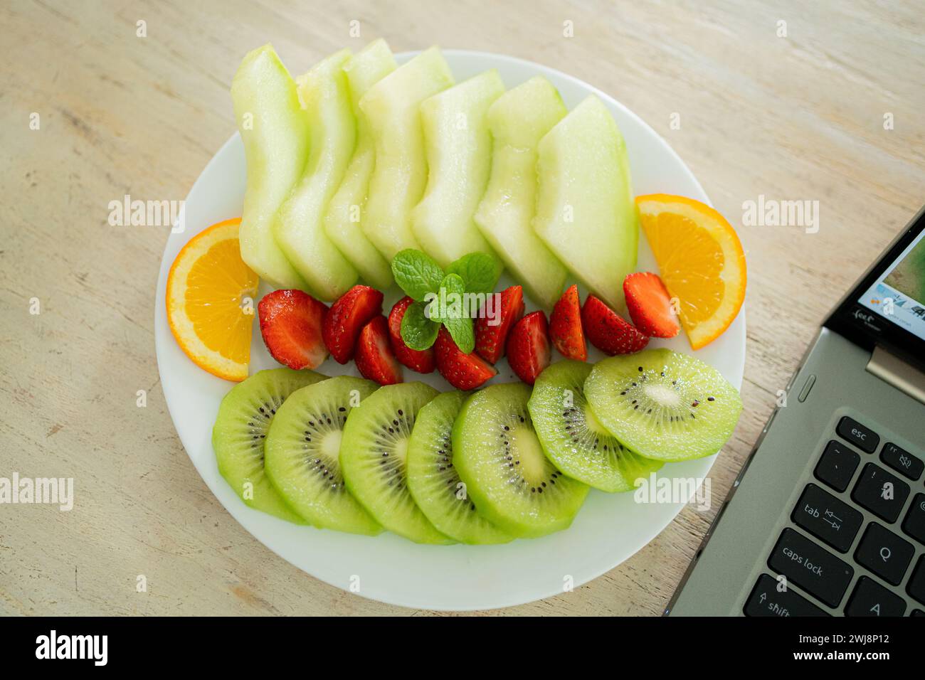 assiette de fruits mélangés contenant du melon, des fraises, des oranges et du kiwi. Banque D'Images