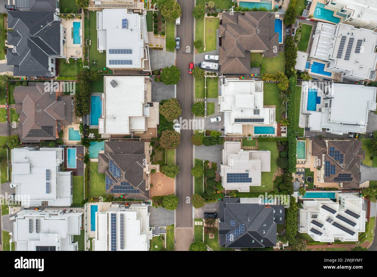 Vue aérienne de haut en bas d'une rue de banlieue bordée de maisons de prestige modernes avec piscines et toit solaire dans la périphérie de Sydney, en Australie. Banque D'Images