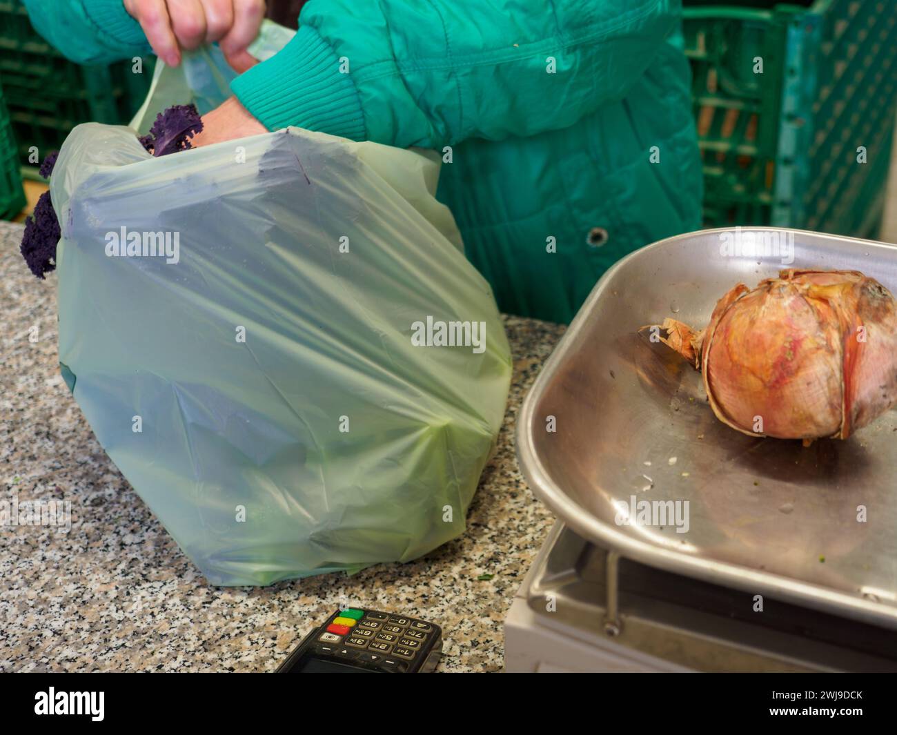 le vendeur de femme senior pèse gros oignon rose organique dans une balance à l'image haute résolution de magasin de détail Banque D'Images