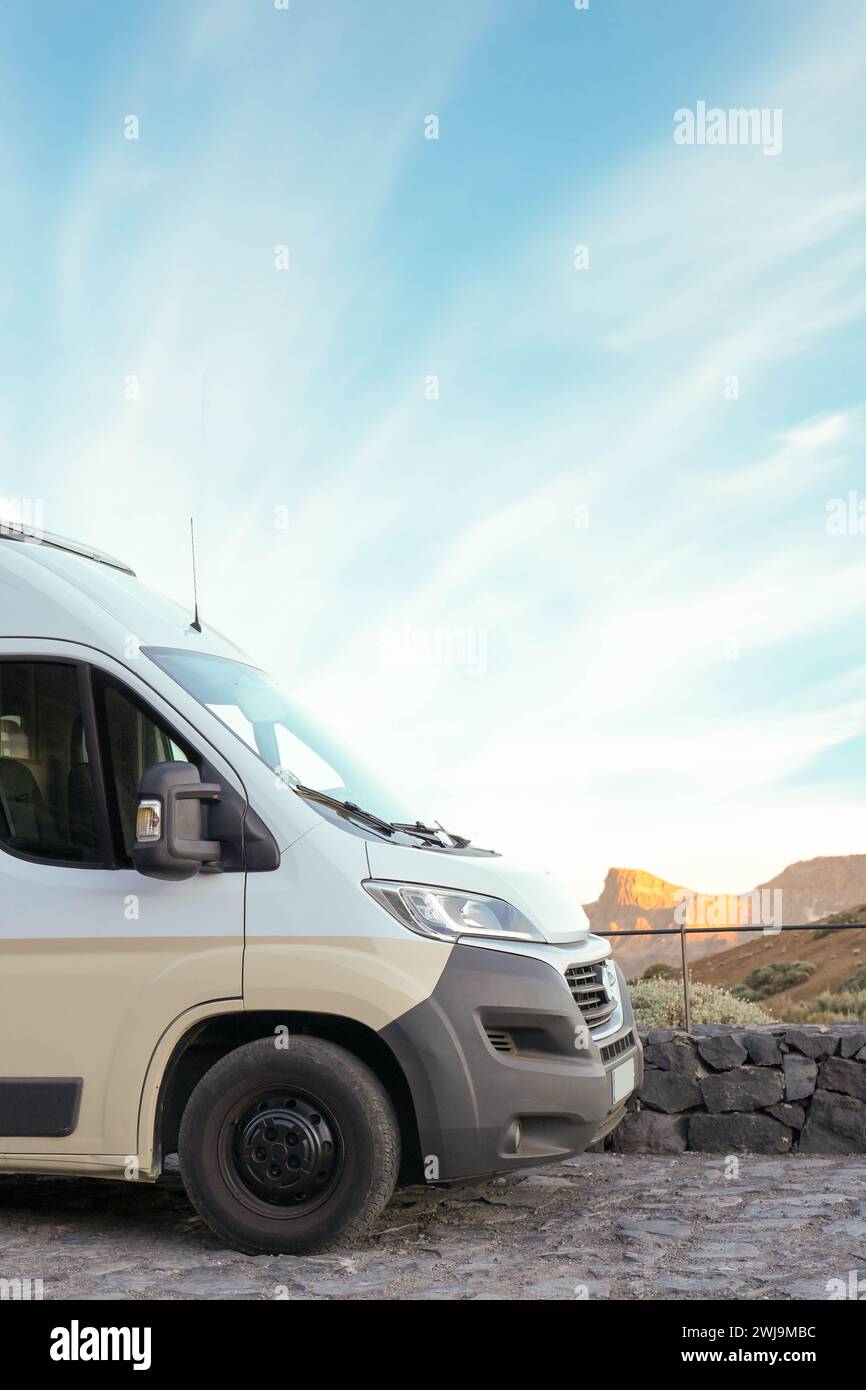 Un camping-car est capturé installé sur la toile de fond tranquille d'un désert sous la douce lueur du soleil couchant, offrant une retraite paisible dans le Banque D'Images