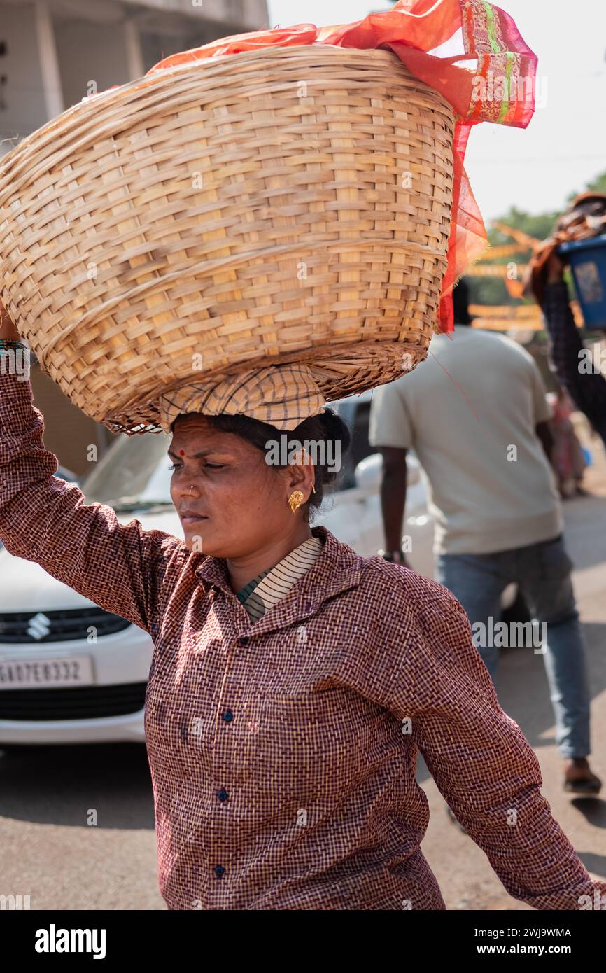 Femme portant un panier sur la tête, Goa India. Femme indienne avec un grand panier sur la tête. En Inde, c'est une façon populaire d'apporter des choses lourdes. Rue Banque D'Images