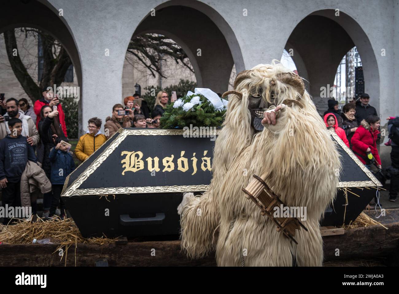 Busó marchant à côté du cercueil - l'un des symboles du Mohács Busójárás 2024 - pendant la procession de Buso, avec la foule debout sur le côté Banque D'Images