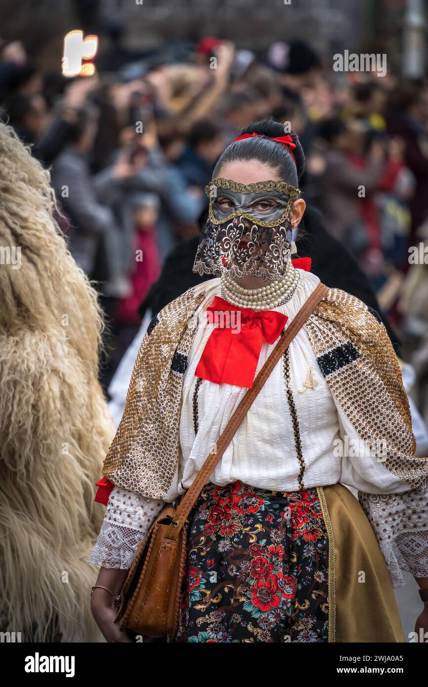 Mystérieuse et belle femme Sokac marchant dans la procession de Buso à Mohács Busójárás 2024, avec la foule en arrière-plan Banque D'Images