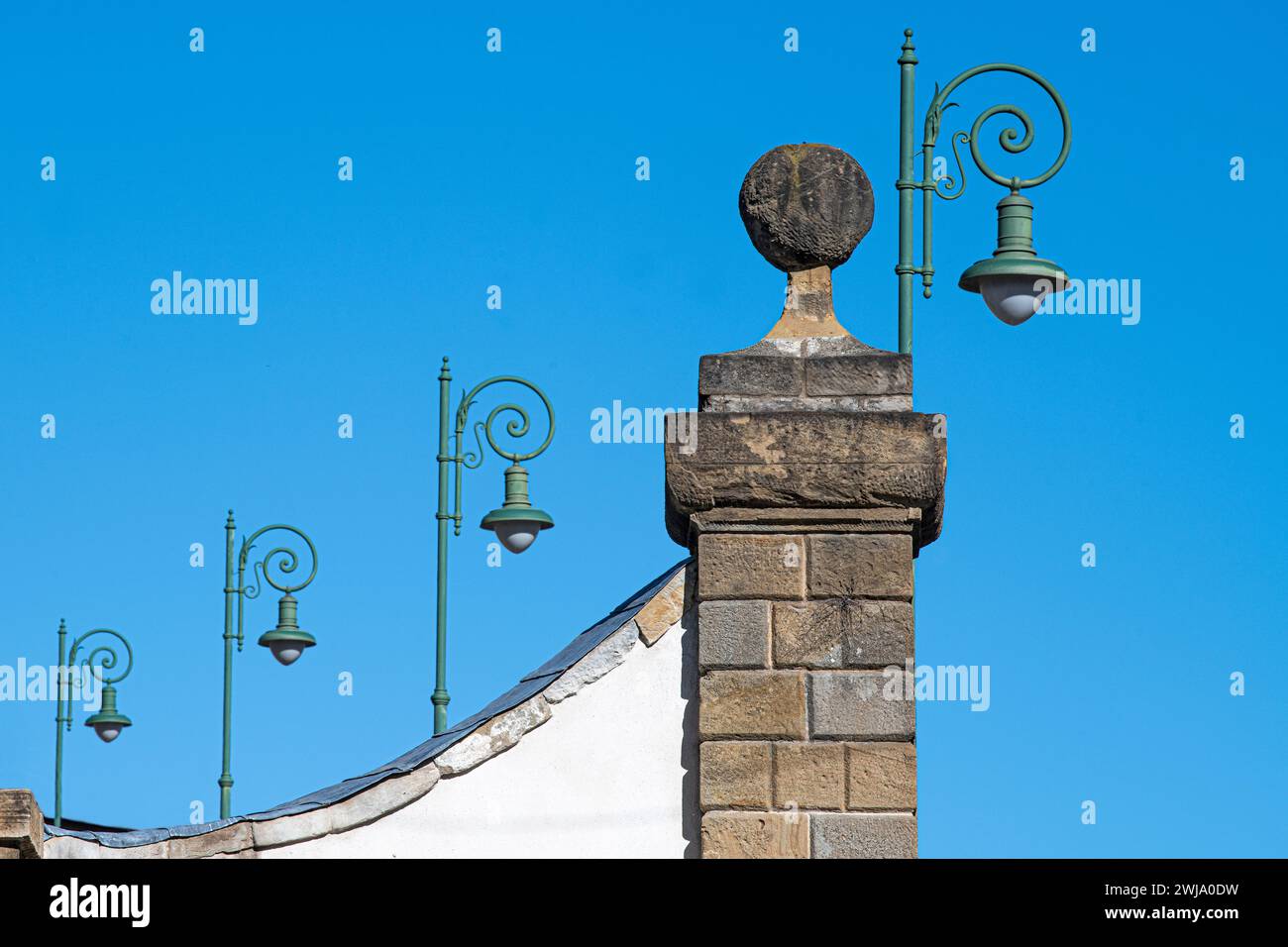 Lanternes de fer antque vertes dans une rangée contre un ciel bleu sur un vieux mur en Italie Banque D'Images