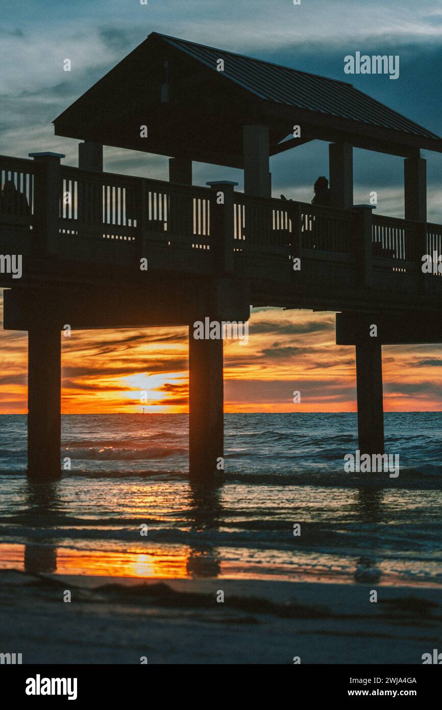 Une scène tranquille de silhouette de coucher de soleil sur un quai de plage de Miami, avec un ciel doré chaud et des vagues douces en Floride, États-Unis. Banque D'Images