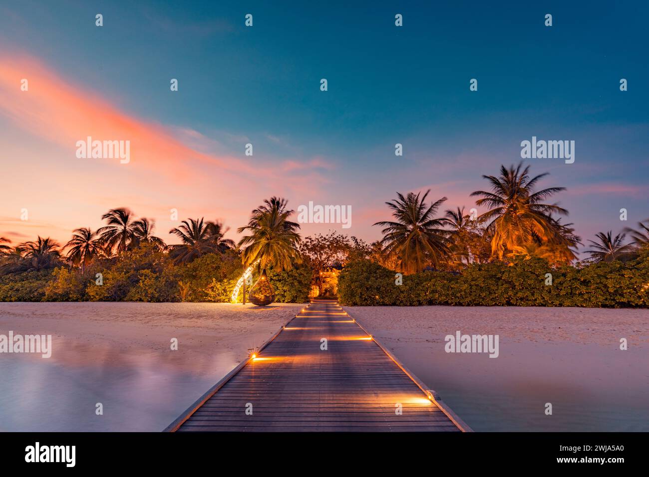Belle côte de plage de coucher de soleil. Ciel coloré nuages de rayons de soleil sur la silhouette des palmiers. Paysage insulaire panoramique, reflets calmes de la mer se détendre tropical Banque D'Images