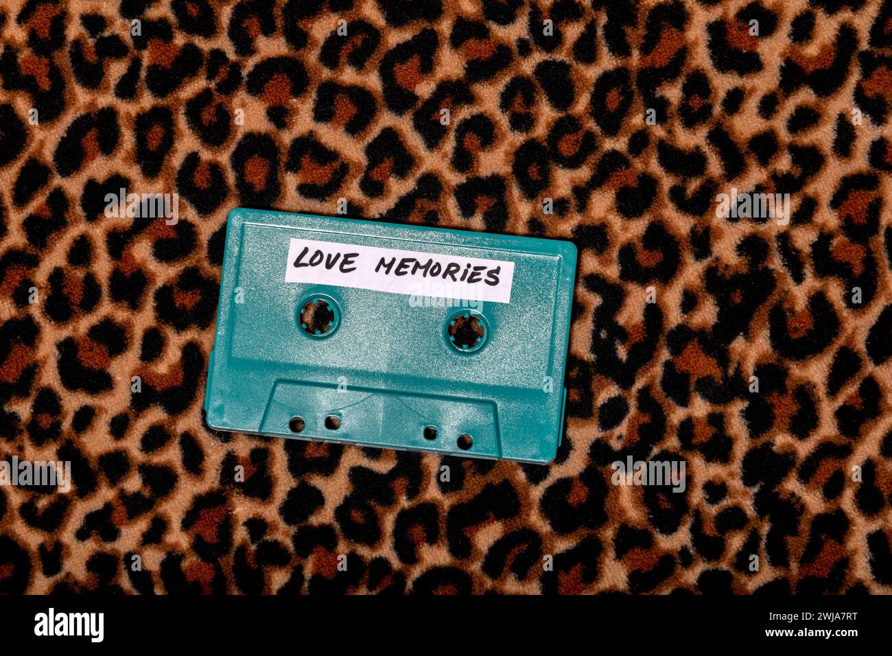 Vue de dessus de cassette vintage avec des roues de ruban adhésif et avec message d'inscription de souvenirs d'amour sur autocollant blanc placé sur fond léopard à la lumière Banque D'Images