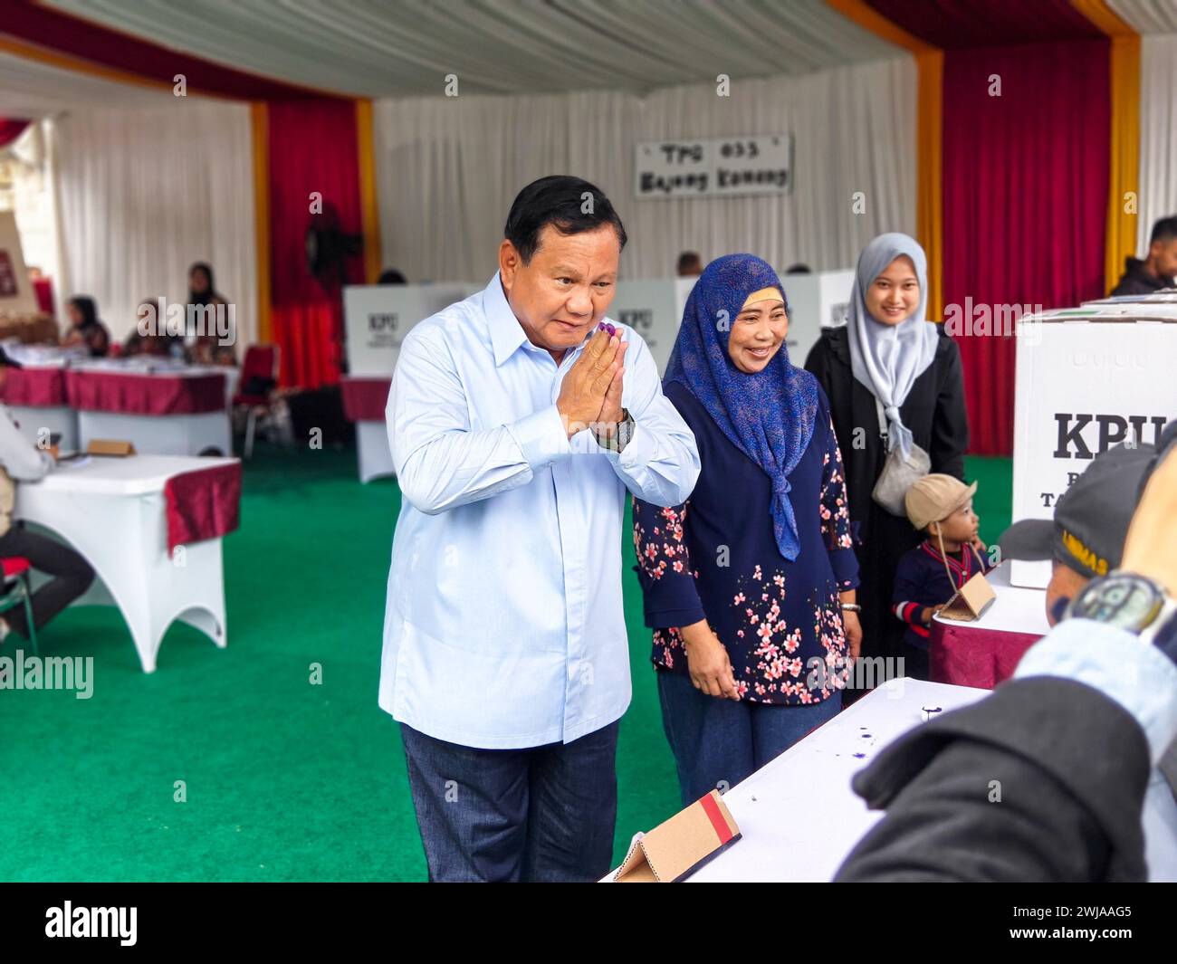 Bogor, Indonésie. 14 février 2024. Cette photo prise avec un téléphone portable montre le candidat présidentiel indonésien Prabowo Subianto (1er, l) saluant des membres du personnel dans un bureau de vote à Bogor, Indonésie, le 14 février 2024. Le vote pour les élections générales en Indonésie a officiellement commencé mercredi matin, selon la Commission électorale générale (KPU) du pays. Crédit : Xu Qin/Xinhua/Alamy Live News Banque D'Images