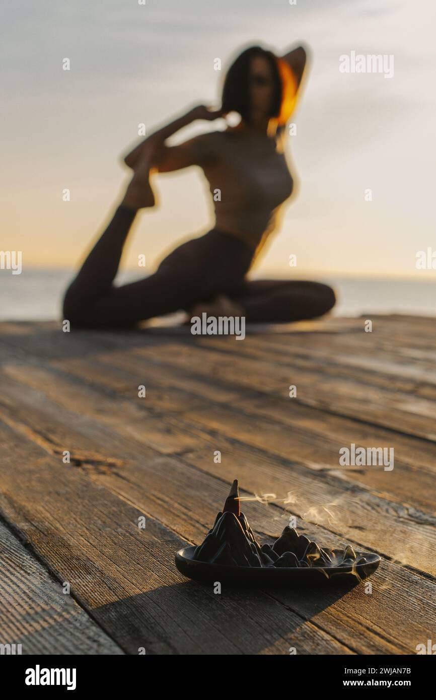 Fille pratiquant le yoga et méditant sur la plage au coucher du soleil. Mise au point sélective. Banque D'Images