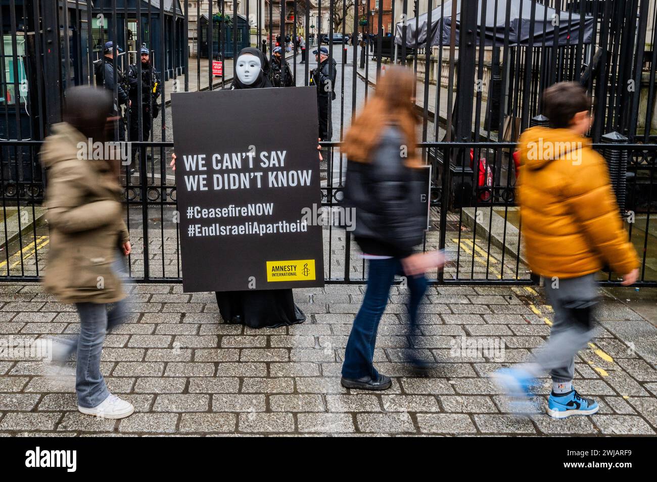 Londres, Royaume-Uni. 14 février 2024. Nous ne pouvons pas dire que nous ne savions pas - Amnesty International UK organise une veillée silencieuse en solidarité avec les civils à Rafah, près de Downing Street. Ils visaient à attirer l'attention sur le sort de quelque 1,4 million de civils palestiniens qui courent un risque aigu lors d'une attaque militaire israélienne de grande envergure contre la ville. Des activistes vêtus de noir et portant des masques blancs ont tenu des déclarations de Palestiniens à Rafah qui ont déjà connu des attaques israéliennes «dévastatrices» contre leurs maisons. Crédit : Guy Bell/Alamy Live News Banque D'Images