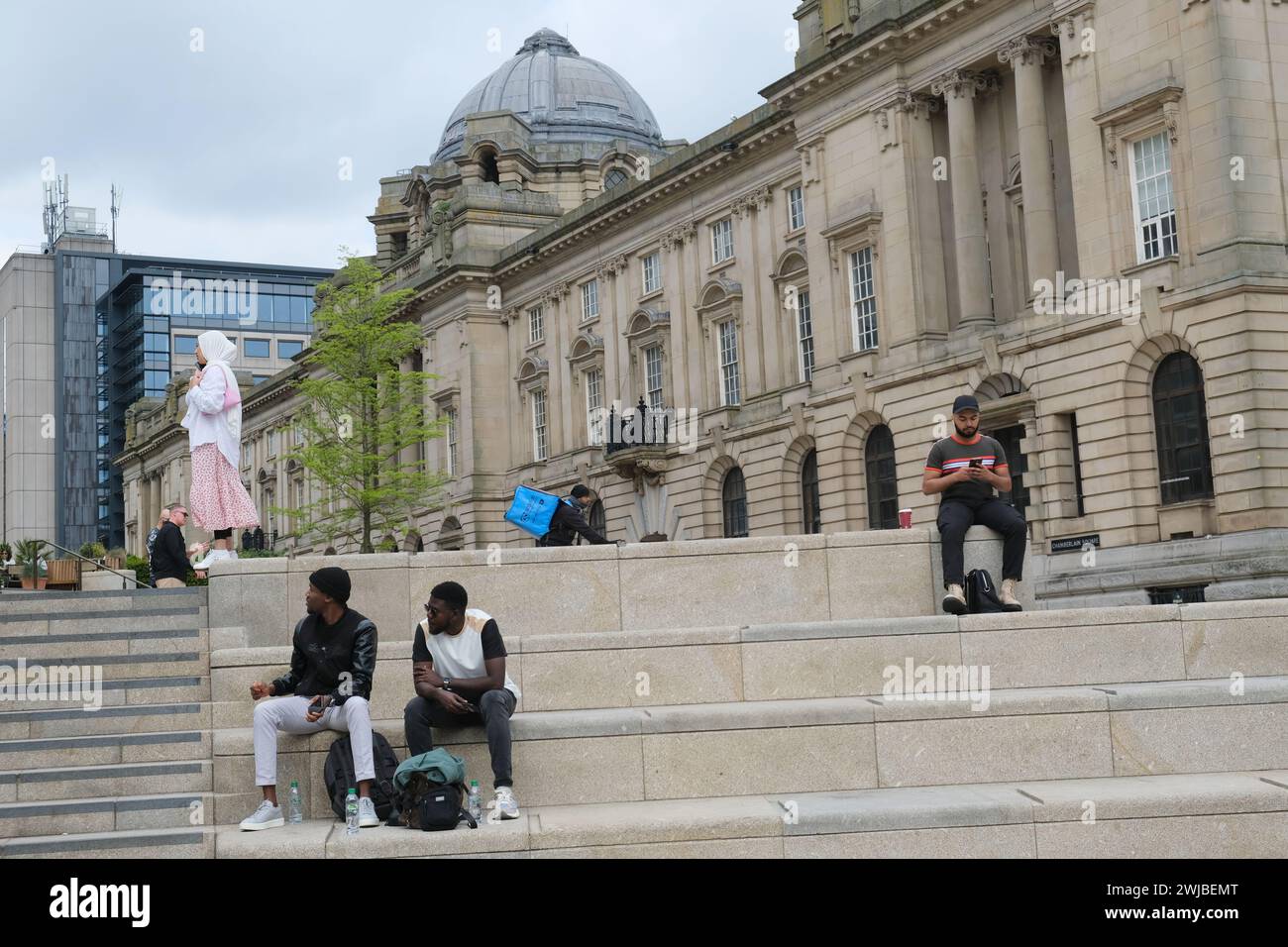 Des gens divers sont assis sur les marches de Chamberlain Square régénéré dans le centre de Birmingham, au Royaume-Uni Banque D'Images Des gens divers sont assis sur les marches de Chamberlain Square régénéré dans le centre de Birmingham, au Royaume-Uni Banque D'Images