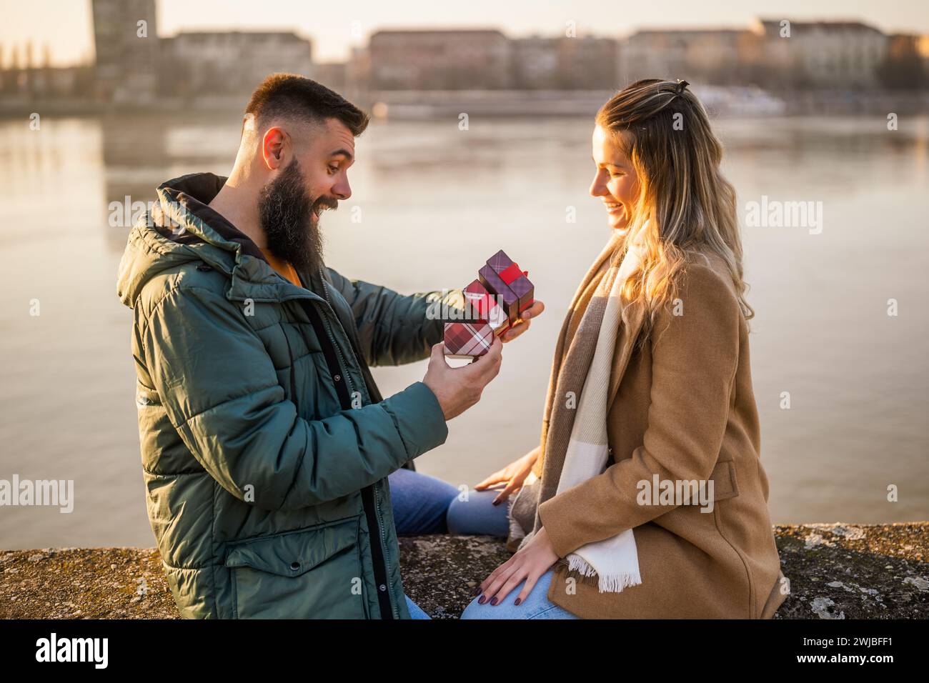 Femme donnant des cadeaux à son homme pendant qu'ils aiment passer du temps ensemble à l'extérieur. Banque D'Images
