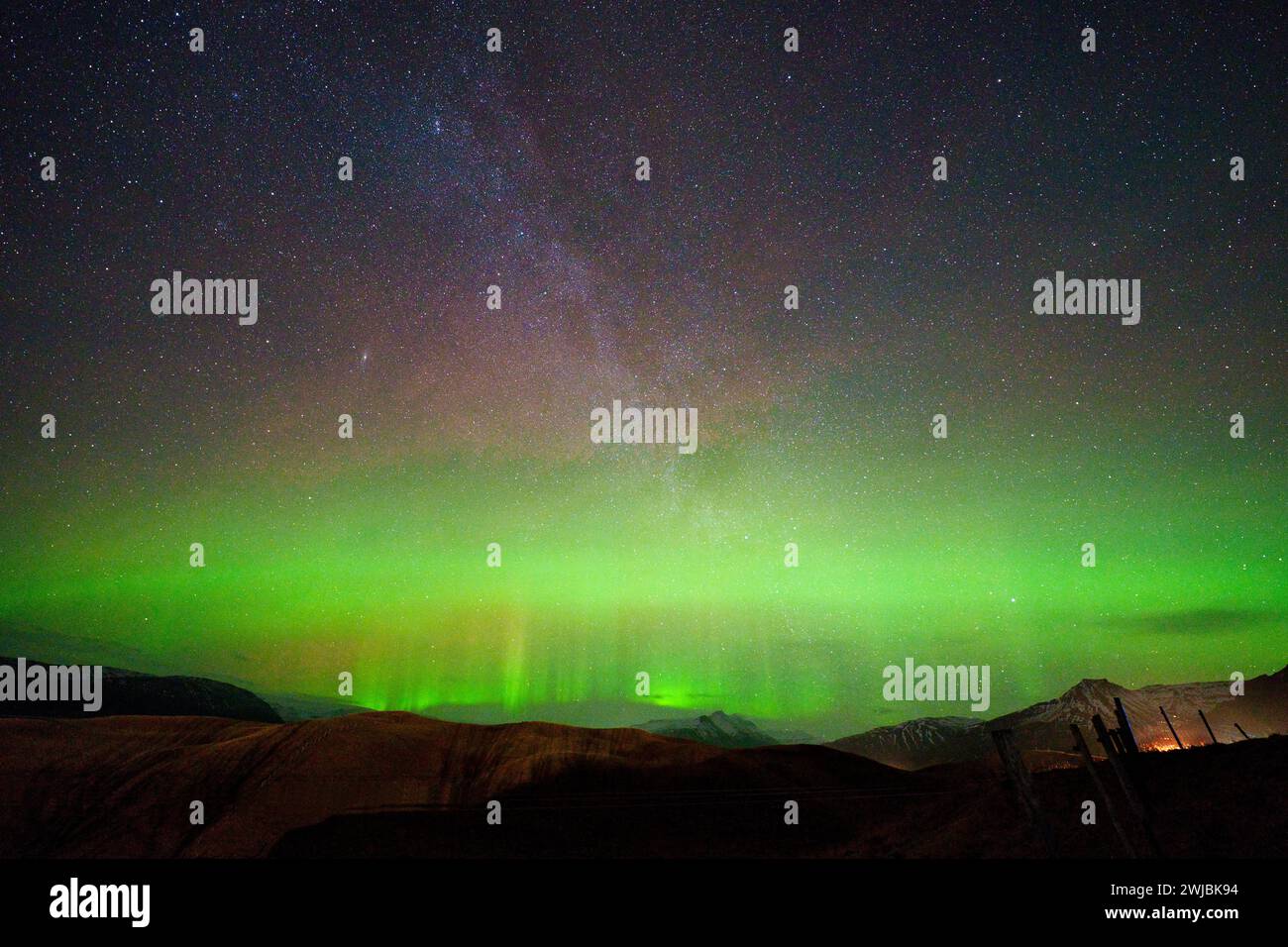 Aurore avec des piliers visibles entre les étoiles de la voie lactée au-dessus et les collines au-dessous. Une longue exposition fait ressortir les verts et les violets dans le ciel. Banque D'Images Aurore avec des piliers visibles entre les étoiles de la voie lactée au-dessus et les collines au-dessous. Une longue exposition fait ressortir les verts et les violets dans le ciel. Banque D'Images