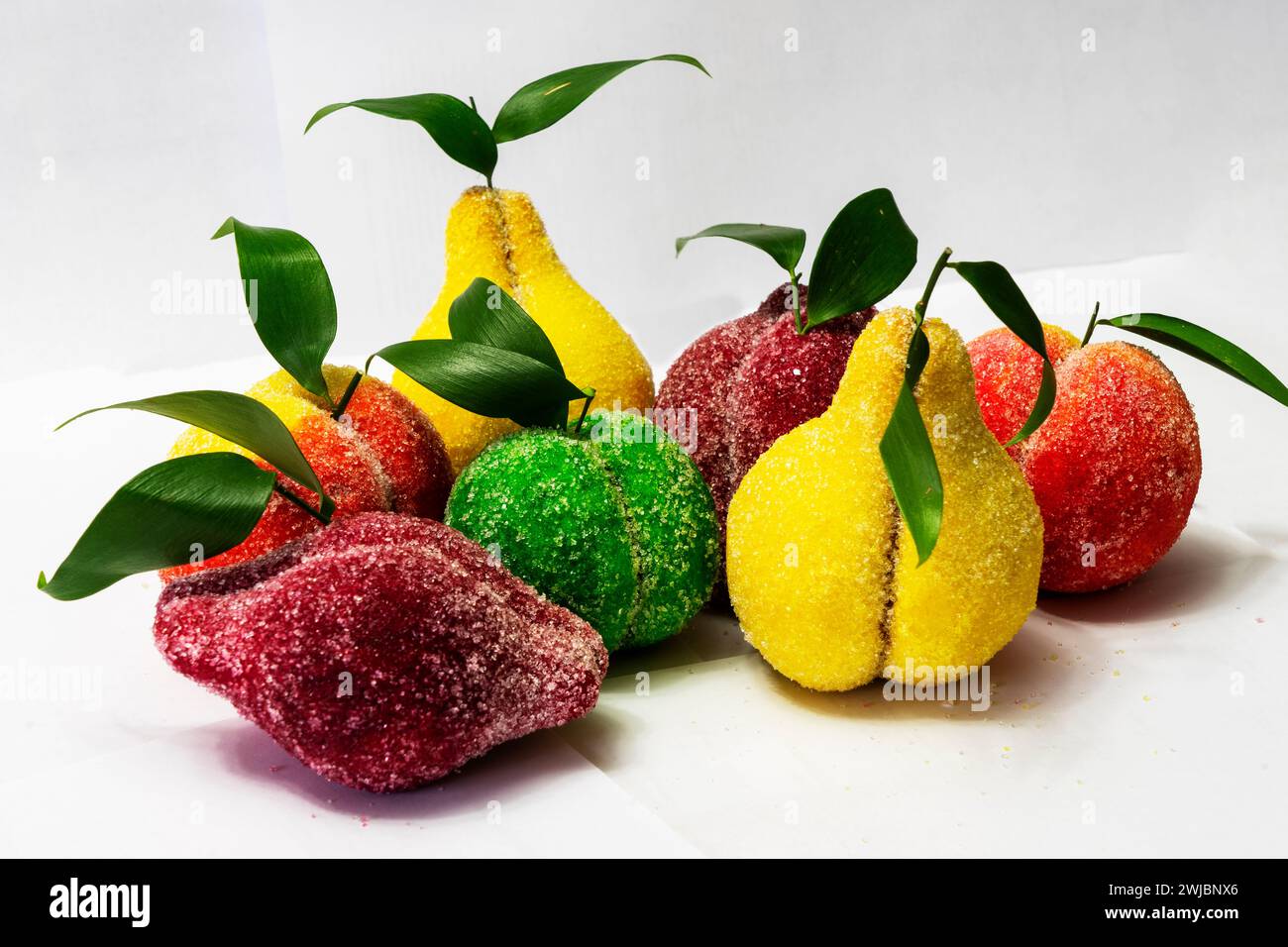 Bonbons faits de pâte sous forme de fruits, pomme, poire, prune et alchi sur fond blanc Banque D'Images