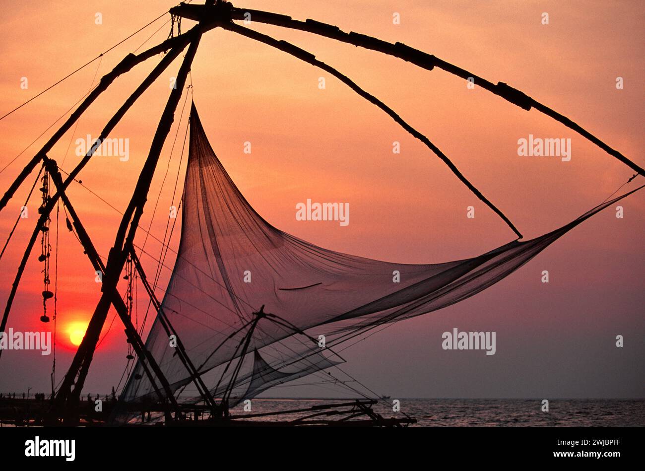 Kochi ou Cochin Inde coucher du soleil une mer calme et le filet de pêche chinois Banque D'Images