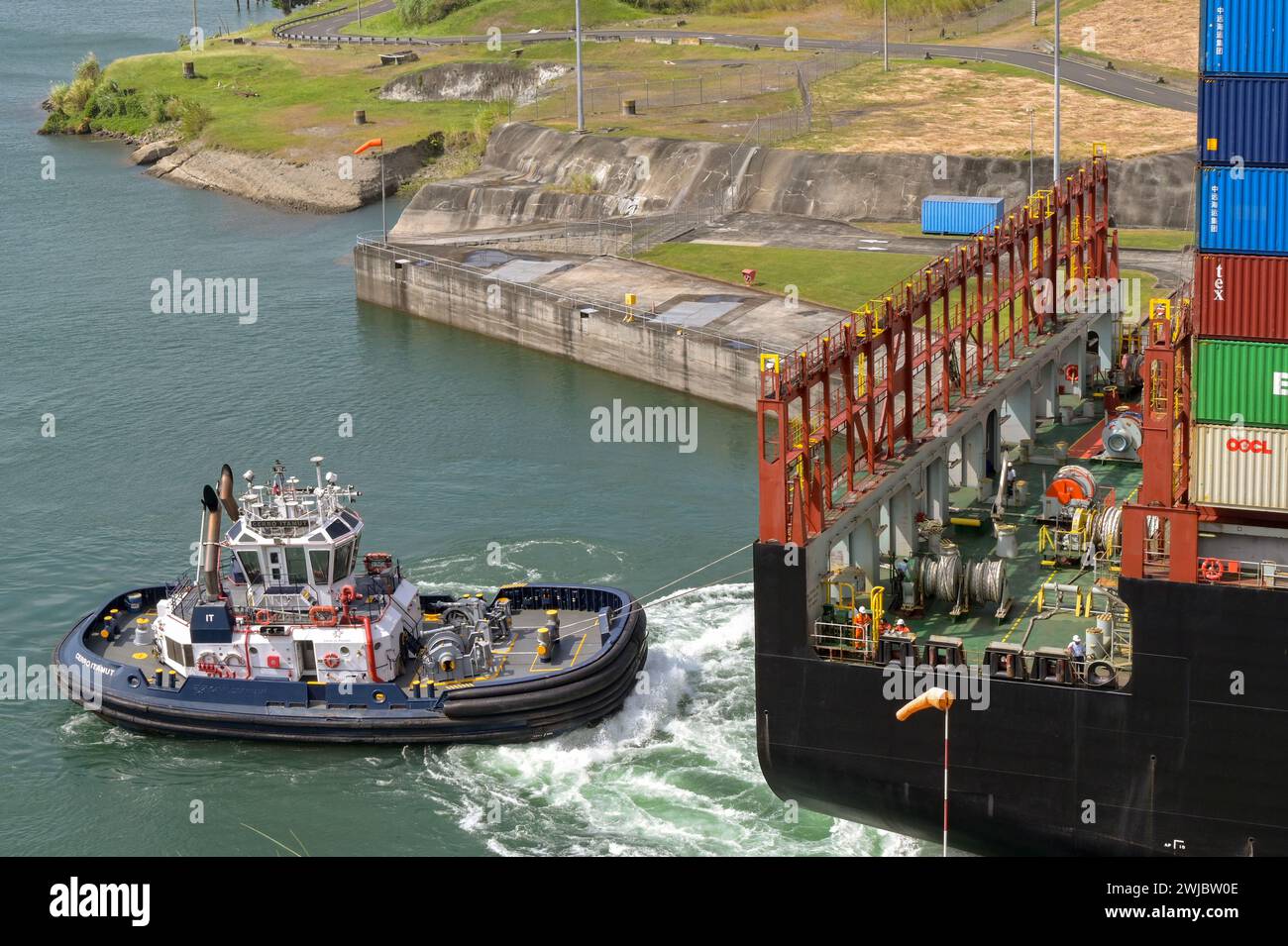 Colon, Panama - 22 janvier 2024 : remorqueur qui envoie un grand porte-conteneurs passer par les écluses d'Agua Clara sur le canal de Panama Banque D'Images