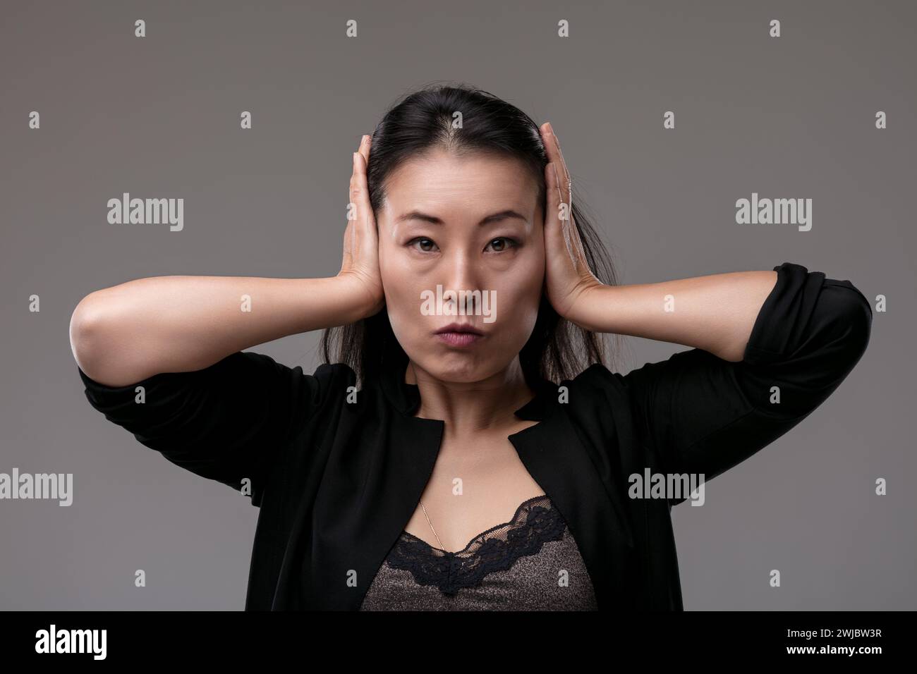 Avec les mains sur les oreilles, elle semble fermer le bruit excessif ou chercher à soulager le stress Banque D'Images