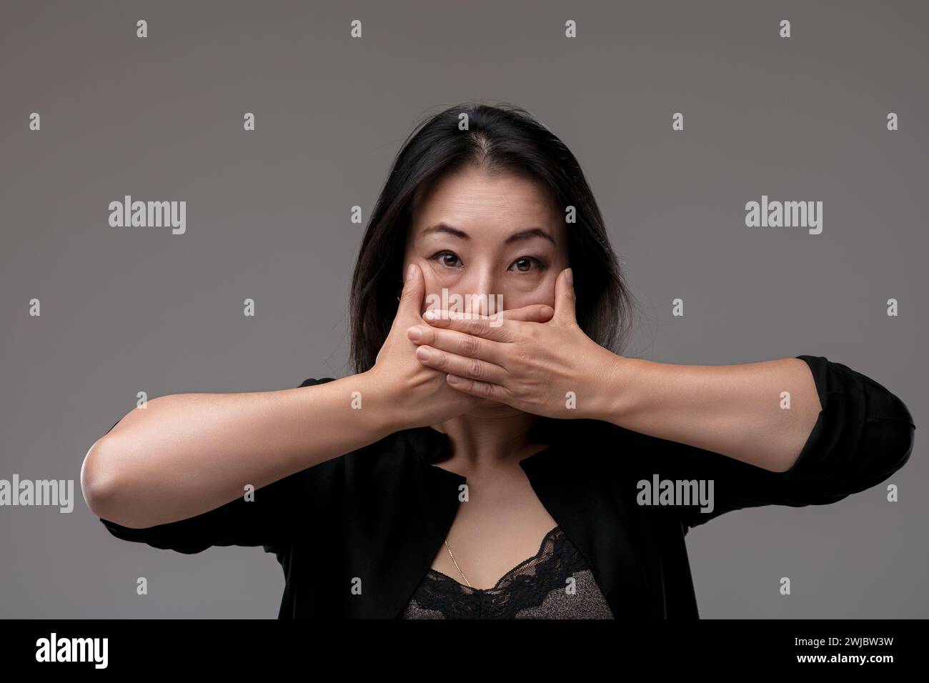 Avec sa bouche couverte par ses mains, elle dépeint un moment de silence, peut-être dû à des nouvelles inattendues Banque D'Images