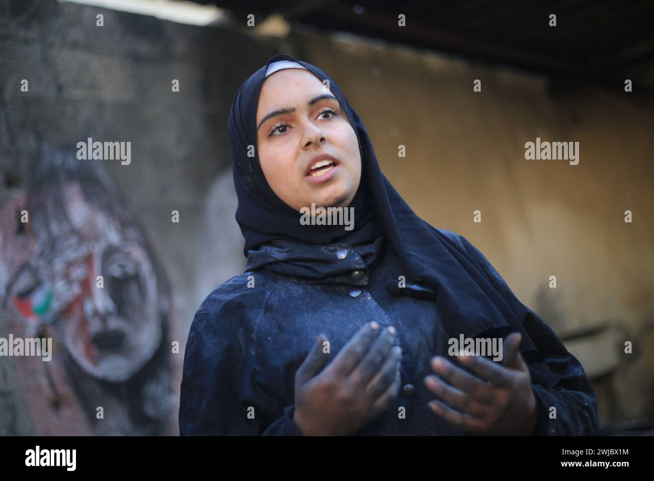 Deir Al Balah, Territoires palestiniens. 14 février 2024. L’artiste palestinienne Menna Hamouda, 21 ans, s’exprime lors d’une interview avec l’Agence de presse allemande (dpa). Crédit : Mohammed Talatene/dpa/Alamy Live News Banque D'Images